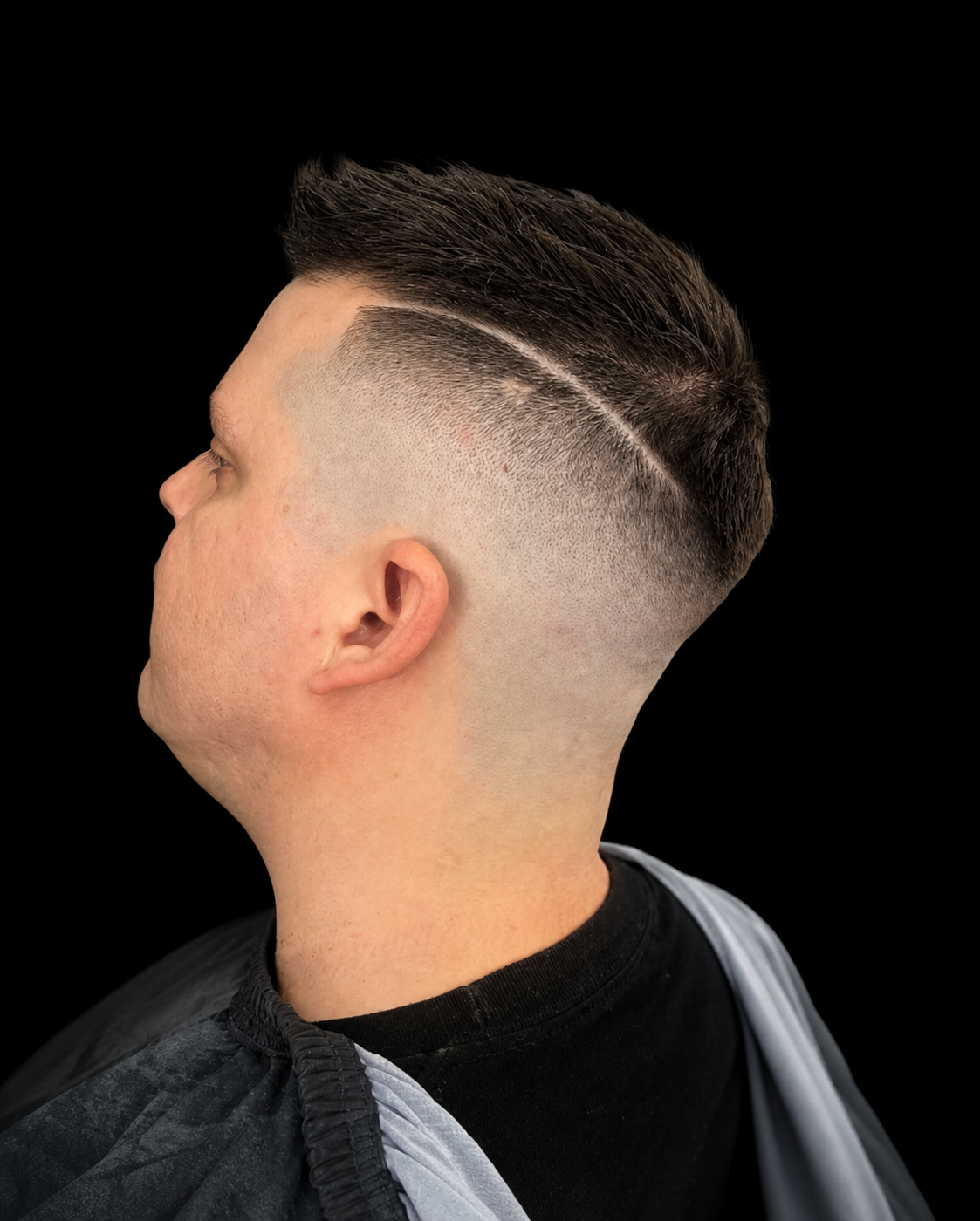 Detailed line design and skin fade against a clean black portrait background